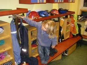 Kind auf einer Bank der Garderobe stehend